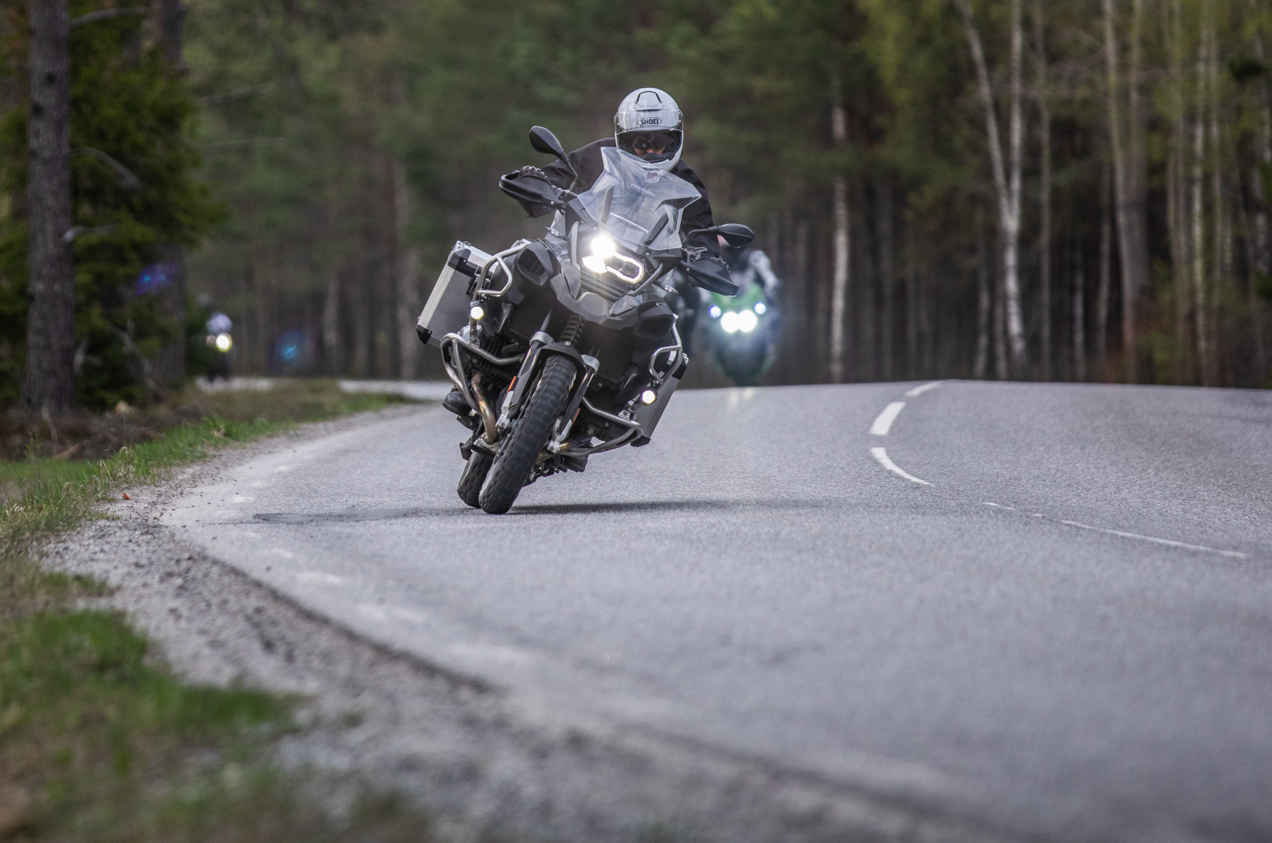 Motorcyklist på asfalterad väg medföljande motorcykel i bakgrunden